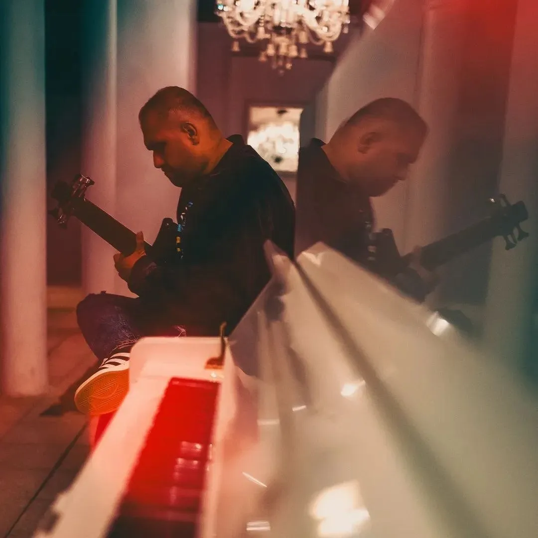 Seated with bass beside a white upright piano