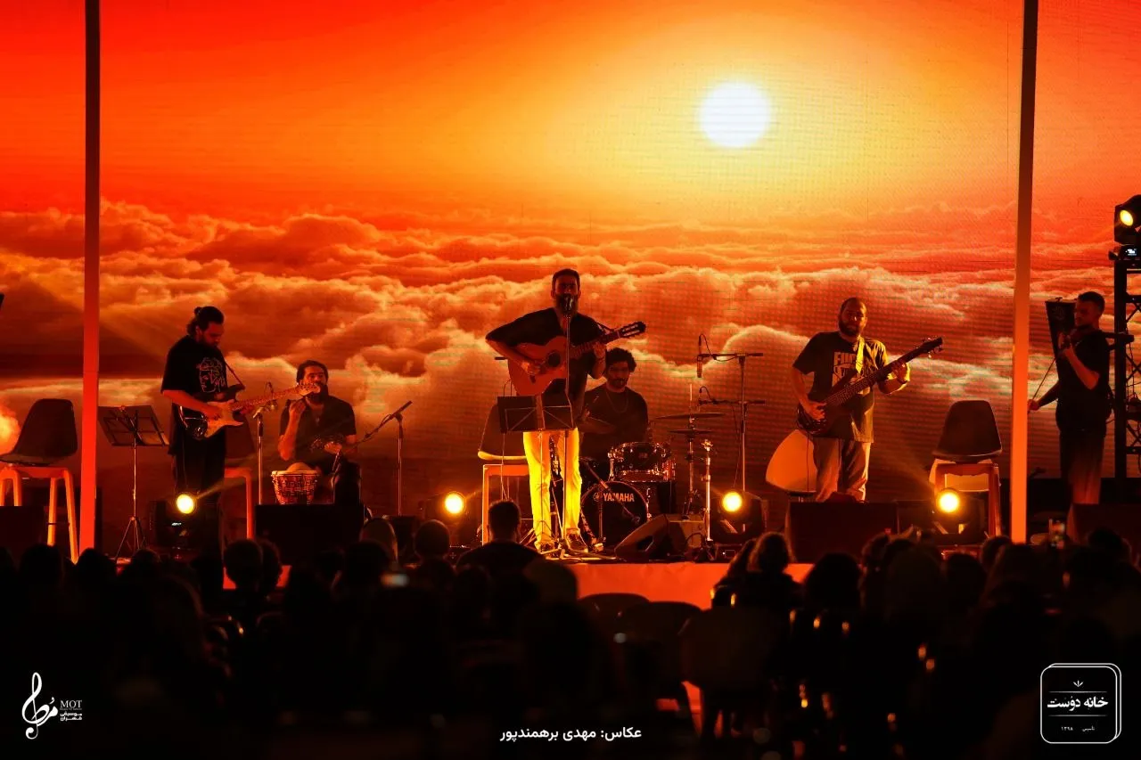 Full band on an outdoor stage in front of a sunset LED backdrop